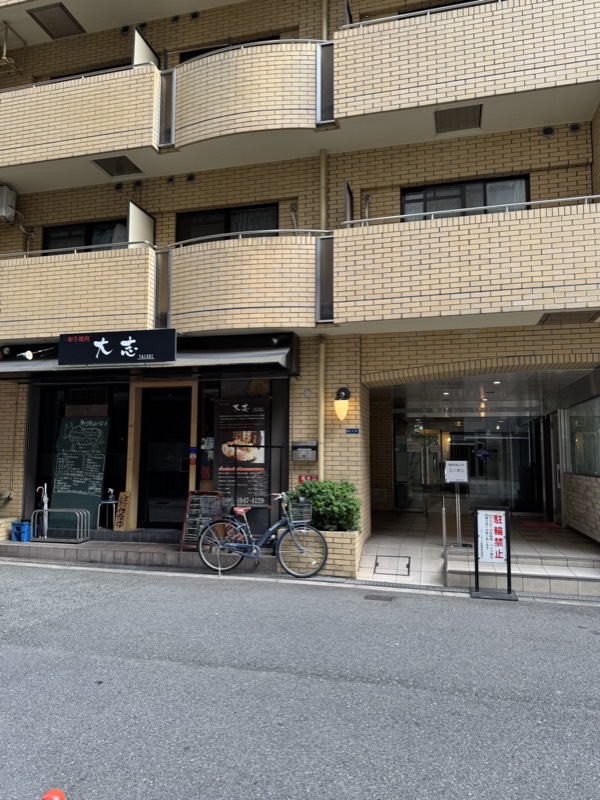 建物の外観。左に焼肉「大志」、その右隣にマンションの入口