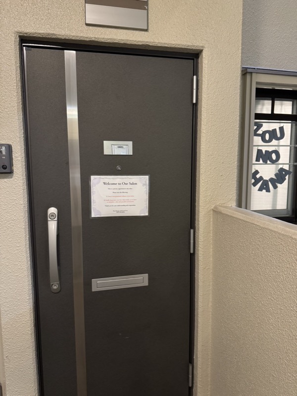 303号室のドア。Welcome to Our Salonの掲示
